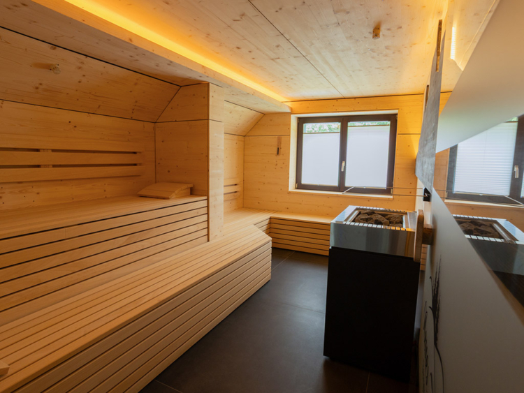 Eine Sauna mit Bänken, einem Sauna-Ofen und einem Fenster